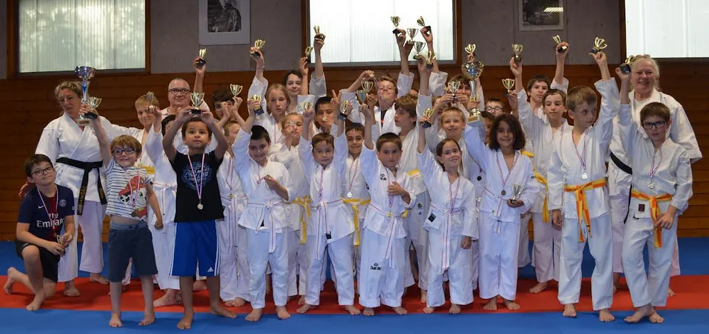 Enfants du club de karaté de Montbonnot souriants, entourés de leurs trophées et médailles de compétition